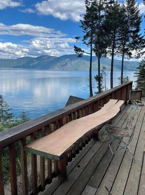 Un muelle de madera con un banco que da a un lago tranquilo y montañas.