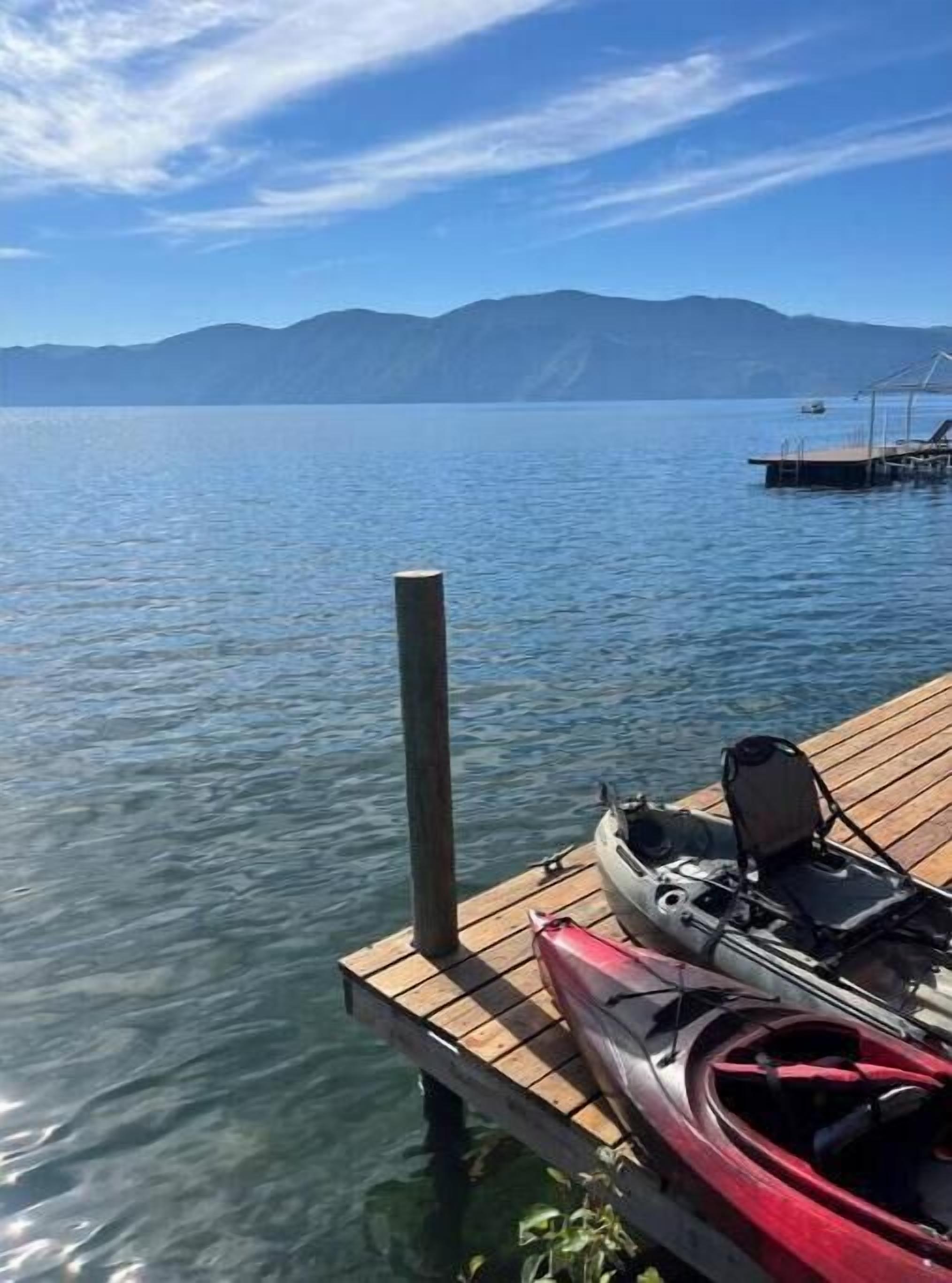 Una banchina di legno che si protende in acque calme, con un kayak e una barca sopra.