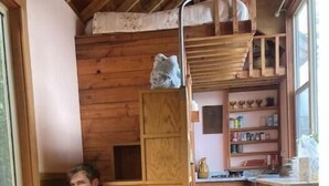 Un intérieur de chalet chaleureux, avec un revêtement en bois, un coin cuisine et une mezzanine aménagée en espace nuit.