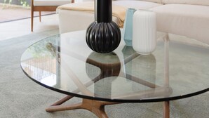 Una sala de estar moderna con una mesa de centro de vidrio, un sofá blanco y una lámpara de pie.