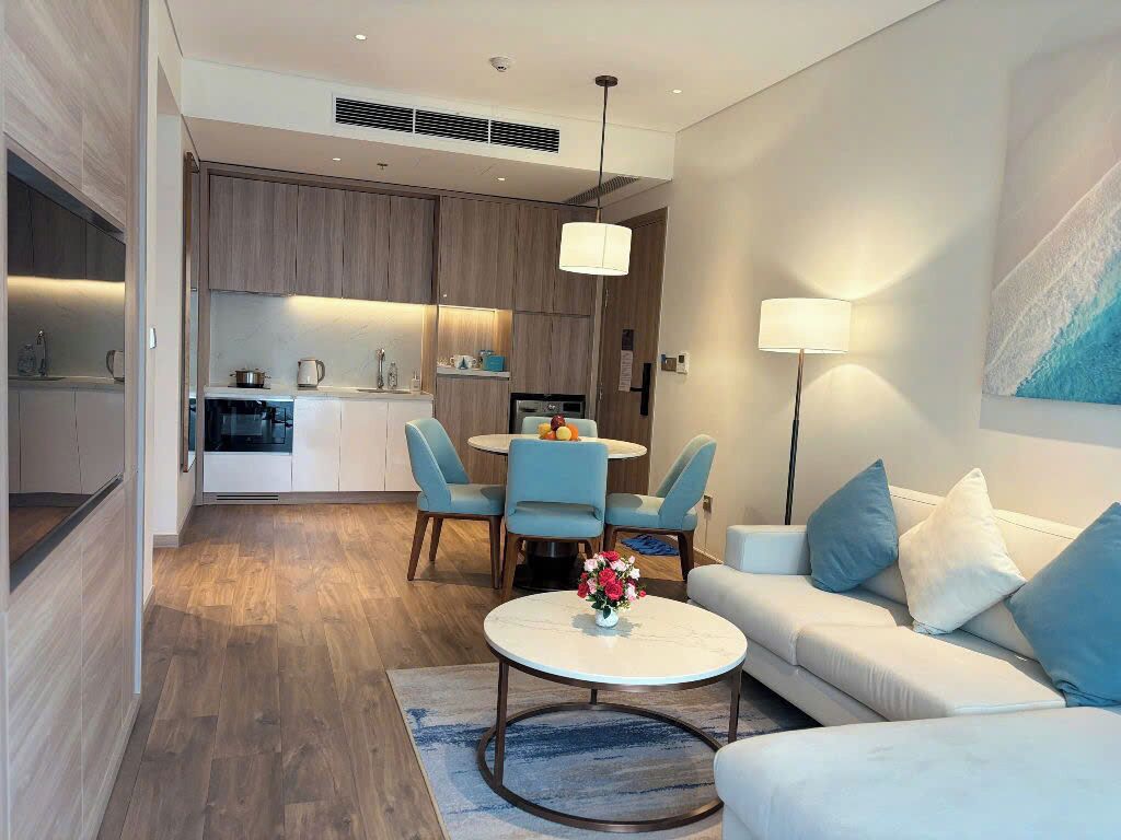 A modern living room with a sofa, coffee table, and dining area with chairs.