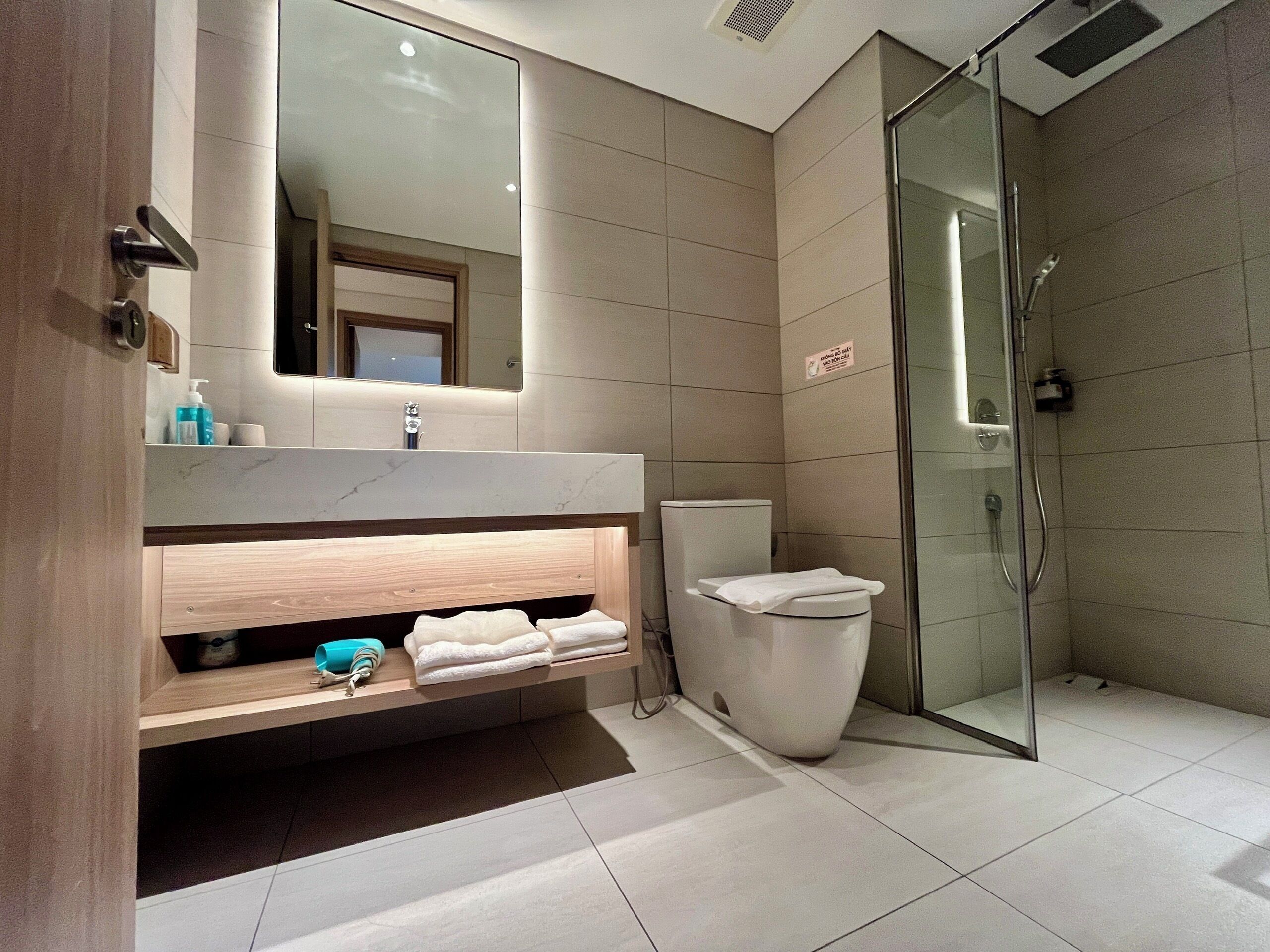 A modern bathroom with a glass shower enclosure, a marble countertop, and a built-in sink.
