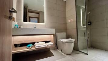 A modern bathroom with a glass shower enclosure, a marble countertop, and a built-in sink.