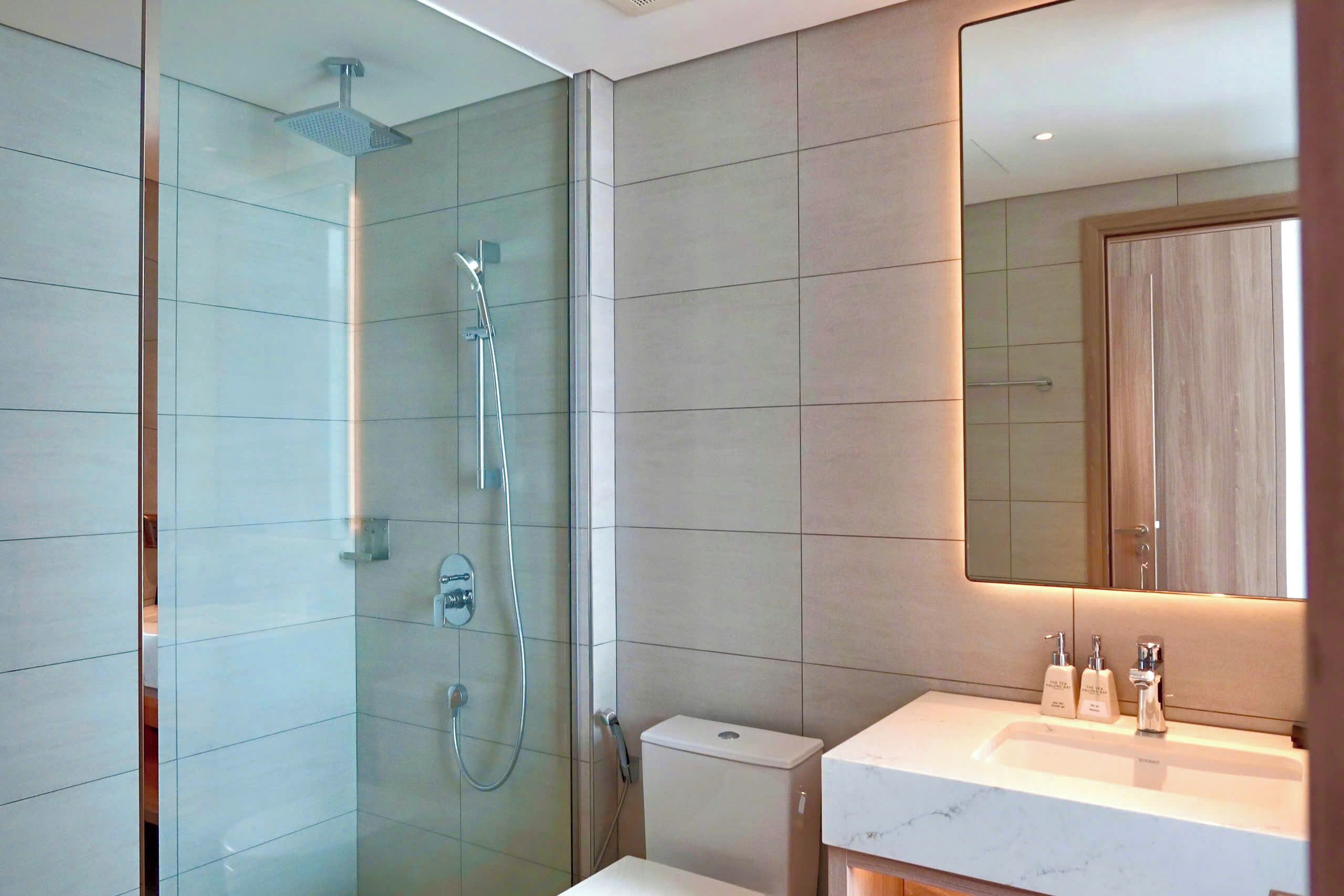 Une salle de bain moderne avec une douche à parois de verre, des toilettes et un lavabo avec un miroir au-dessus.