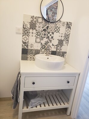 Bathroom features a vanity with a sink, drawers, and mirror.