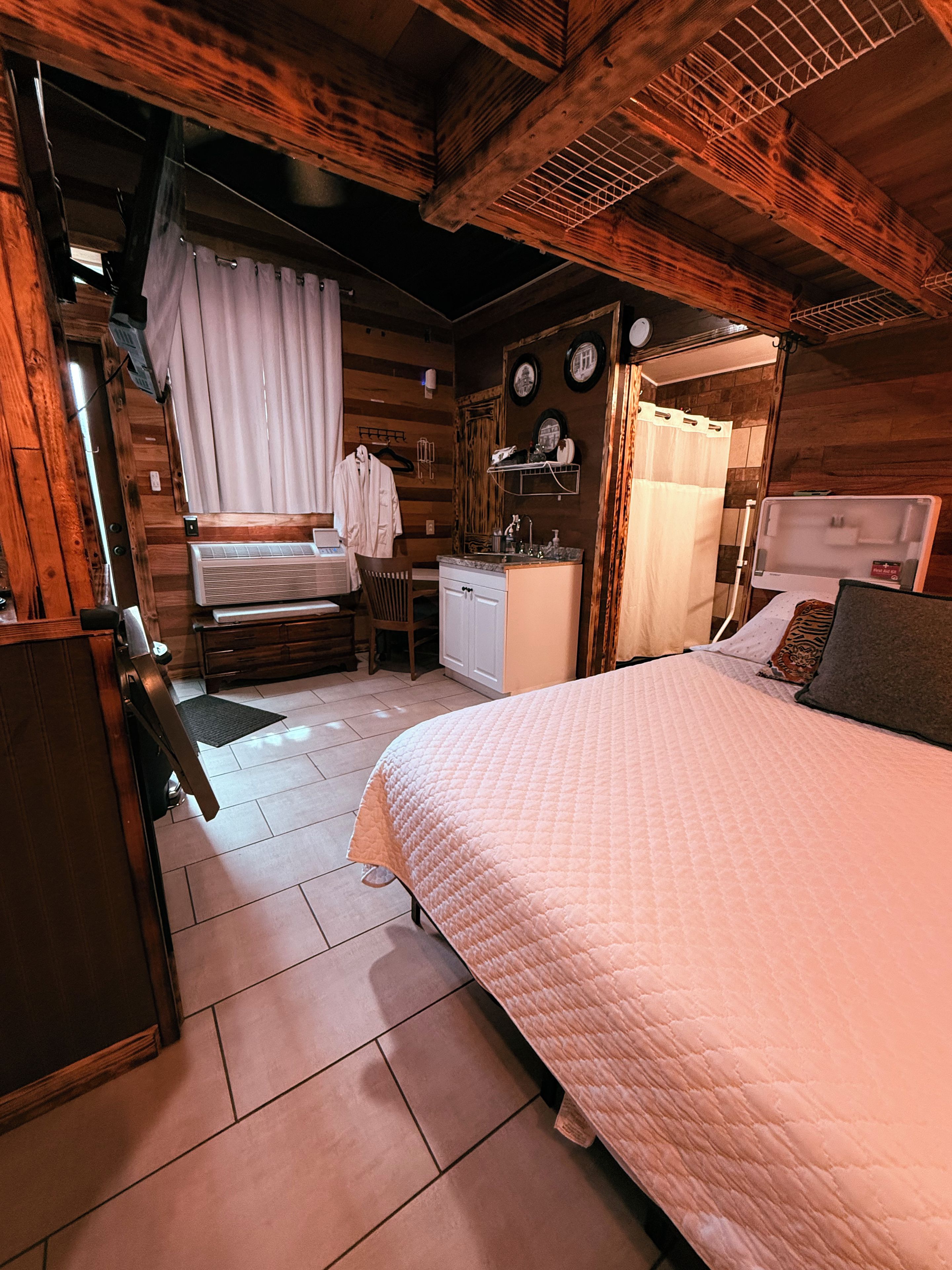 Een gezellige kamer met een bed, een klein bureau, een stoel en een douchegedeelte.