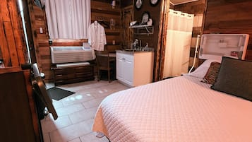 Een gezellige kamer met een bed, een klein bureau, een stoel en een douchegedeelte.