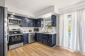 Una cocina moderna con armarios oscuros, electrodomésticos de acero inoxidable y piso de madera.
