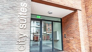 A hotel entrance with a brick facade, a glass door, and a sign indicating "City Suites." - City Suites by Guestz (Chester)