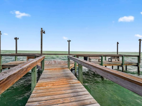 A wooden pier extending into calm water with benches and a railing.