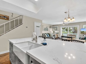 A modern kitchen with a large island, a built-in sink, and a ceiling fan.