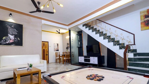 A living room with a pool table, a sofa, a coffee table, and a staircase with a decorative railing.
