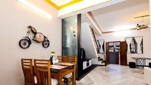 A dining area with a wooden table and chairs, a wall-mounted bicycle, and a large window with a view.