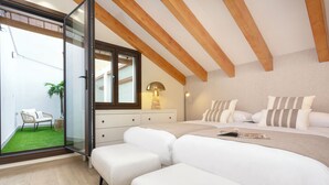 Ein Schlafzimmer mit einem großen Bett, einem Nachttisch, einer Lampe und Blick auf eine grüne Außenanlage.
