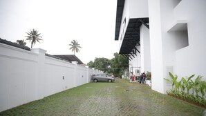 A paved pathway leading to a building with a white exterior and a black roof.
