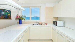 A modern kitchen with a view of the sea, a microwave, and a sink.