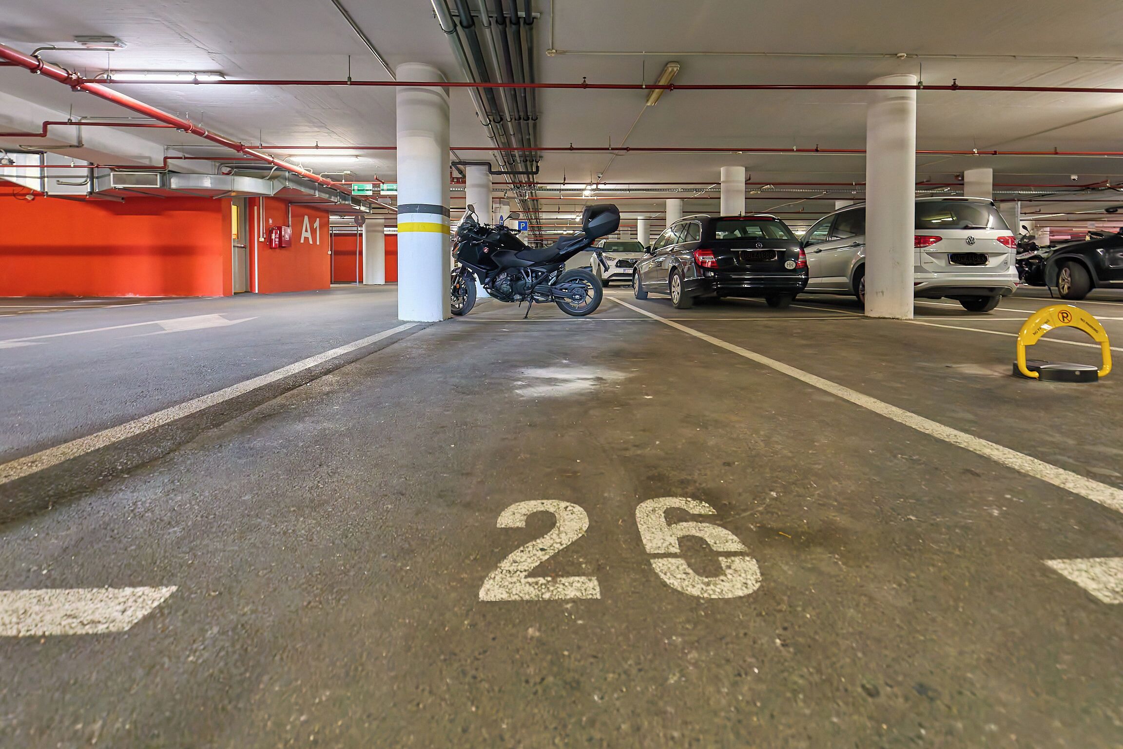 A parking garage with a motorcycle parked in a designated space marked with the number 26.