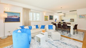 A modern living room with a sofa, ottoman, coffee table, and dining area with chairs and a table.