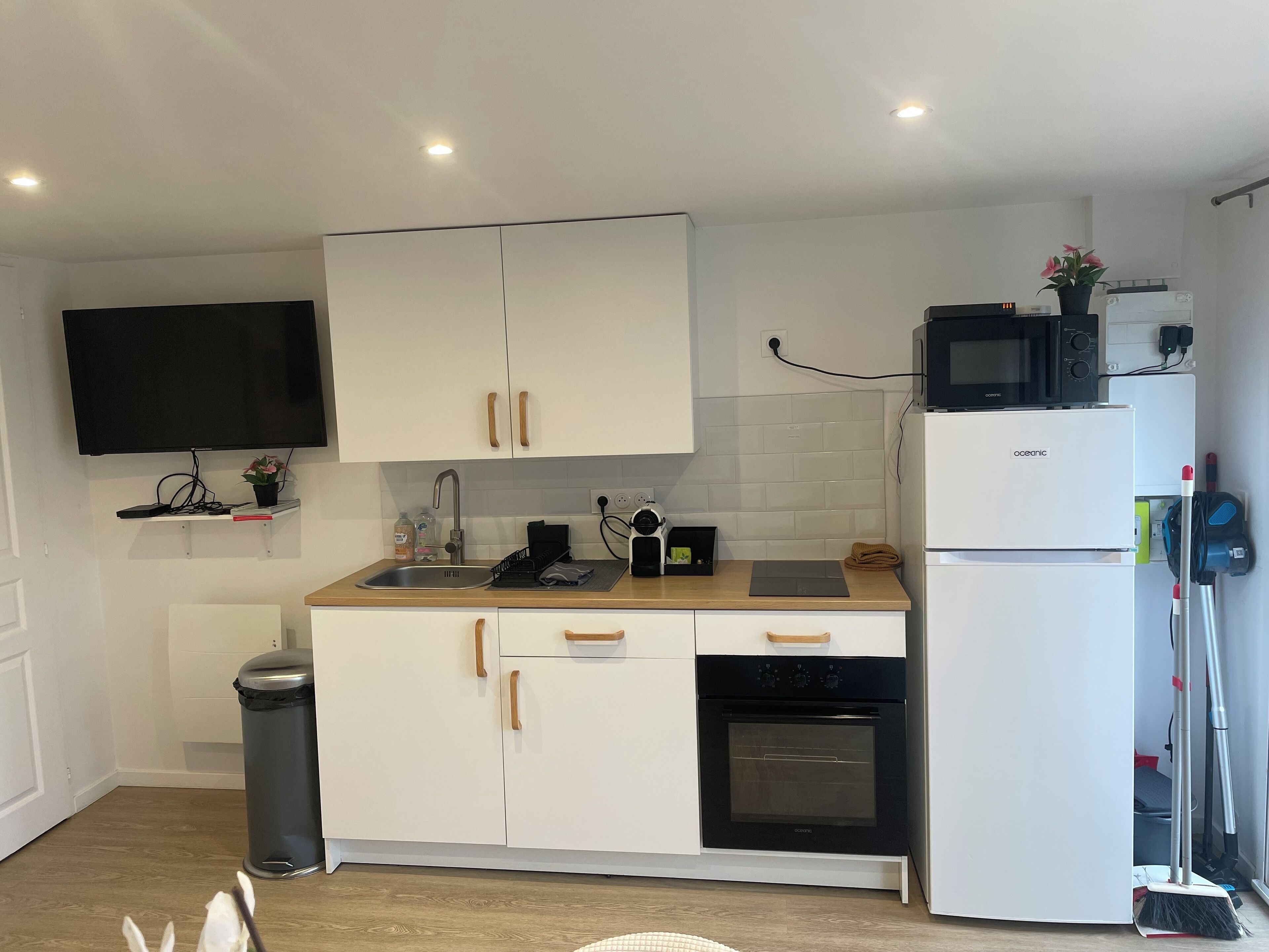 A compact kitchen with white cabinets, a black oven, a microwave, and a sink.