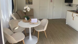 A dining area with a round table, four chairs, a potted orchid, and a card on the table.