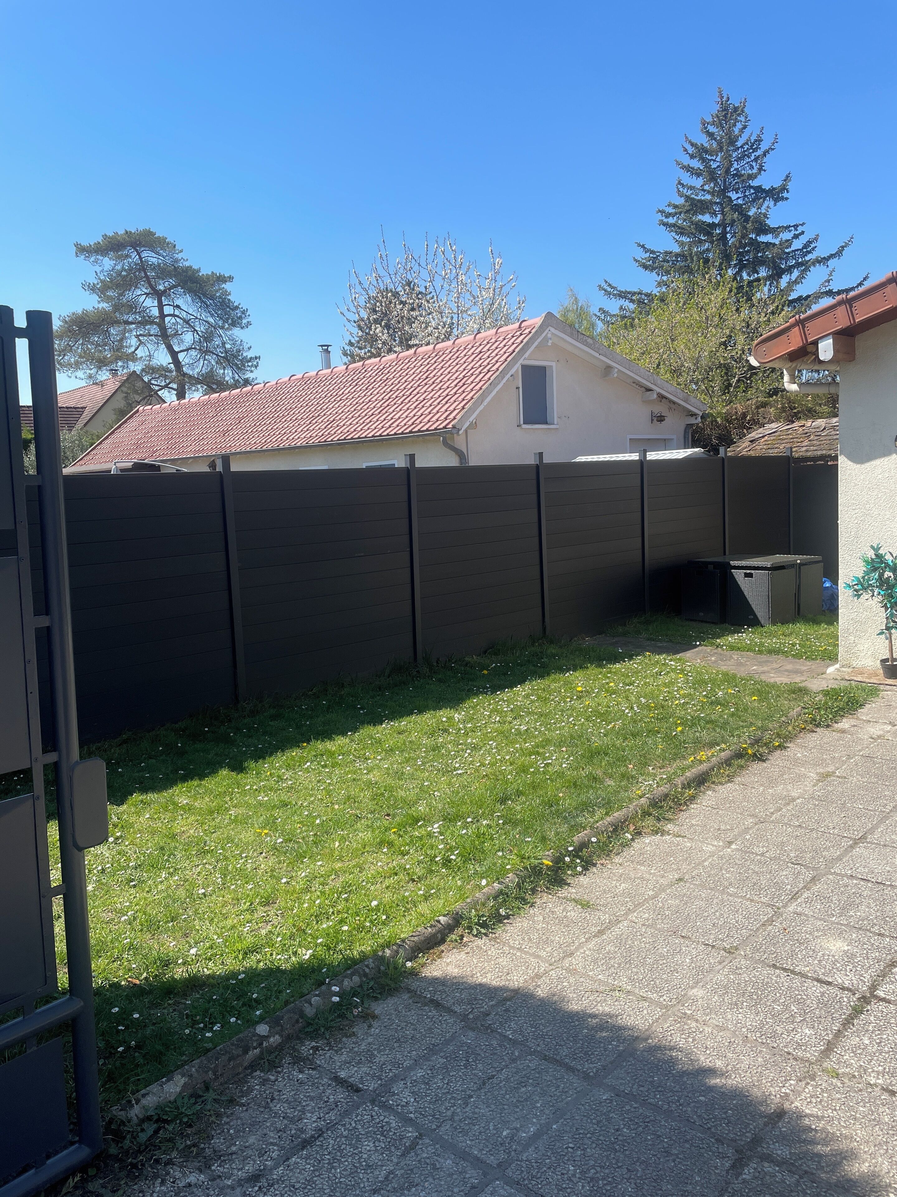 Ein Wohngebiet mit gepflasterter Auffahrt, umzäunter Garten und einem Haus mit roten Ziegelziegeln.