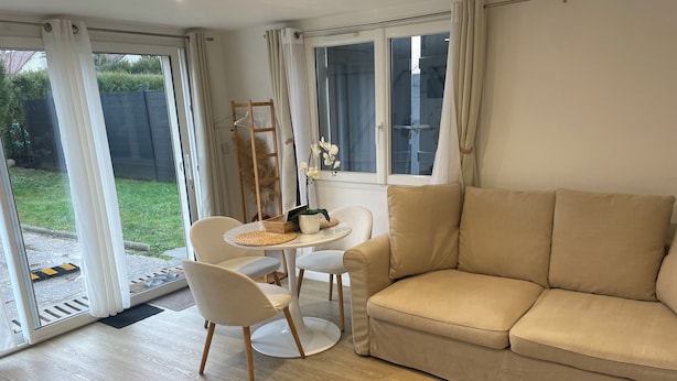 A modern living room with a beige sofa, a round white table, and two white chairs.
