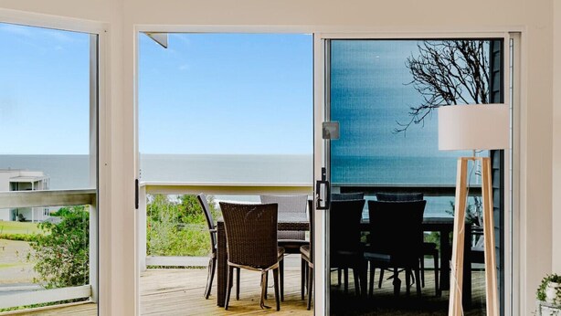 Quarto moderno com porta de vidro deslizante para uma varanda com mesa e cadeiras de jantar.