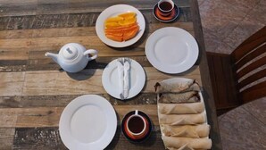 Una mesa de madera con platos, una tetera y alimentos.