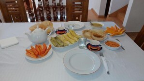 Una mesa de comedor dispuesta con diferentes platos, incluyendo verduras en rodajas, una tetera y tazones de comida.