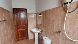 Un baño con puerta de madera, un lavabo blanco, un inodoro y un espejo.