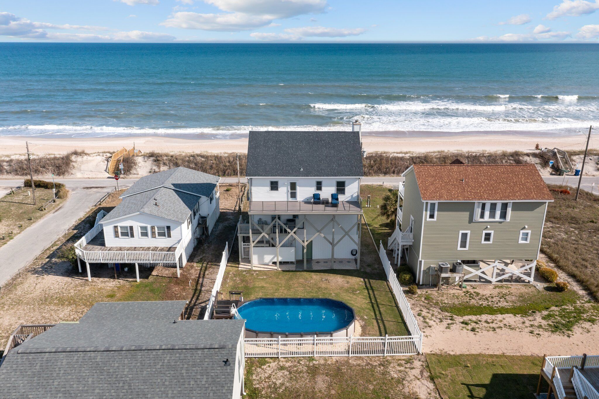 Propiedad frente al mar con piscina, varias casas y vista a la playa.