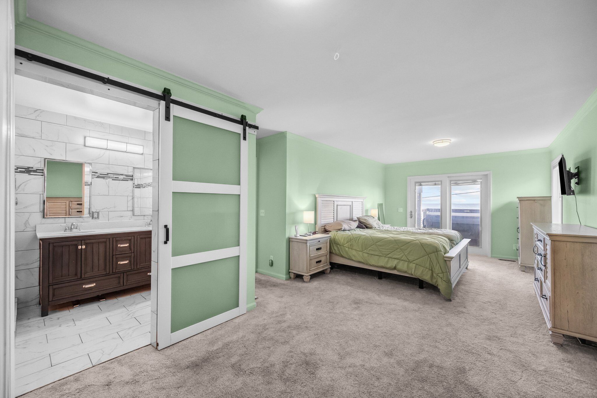Un dormitorio con cama, mesita de noche, cómoda y una puerta corredera que da al baño.