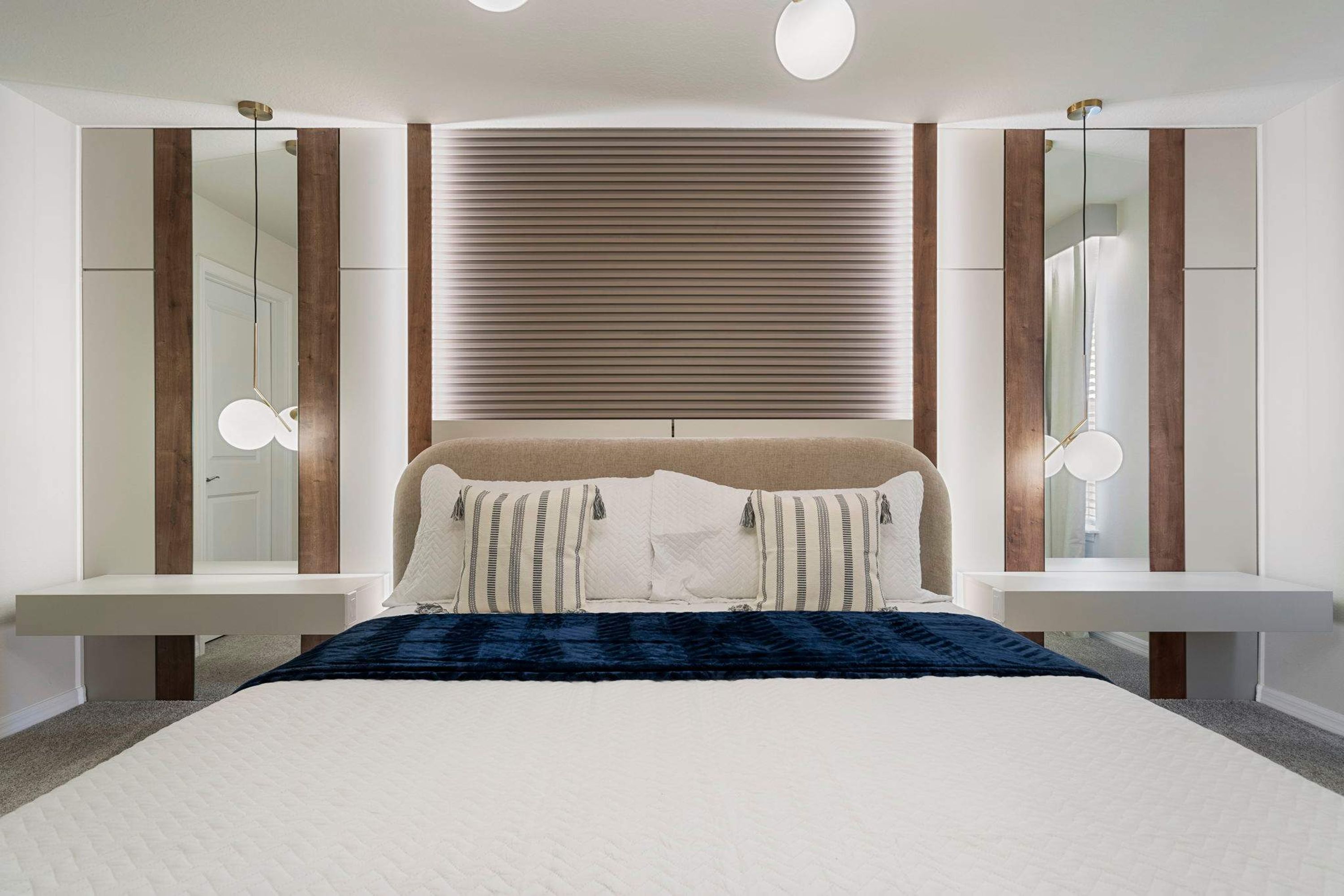 A modern bedroom with a large bed, bedside tables, and a mirror.