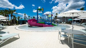 A pool area with a water slide, lounge chairs, and umbrellas. - 1149 Spacious Family 5-bedroom Townhome (Clermont)