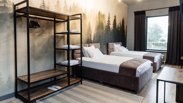 A modern hotel room with two beds, a built-in wardrobe, and a large window. - Avenue Hotel (Uralsk)