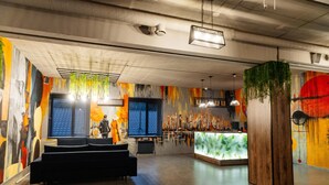 A modern lobby with a reception desk, seating area, and colorful murals. - Avenue Hotel (Uralsk)