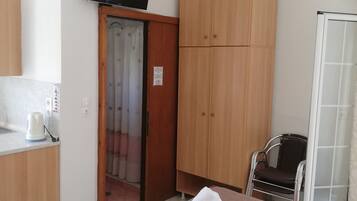 A hotel room with a bed, a television mounted on the wall, a wardrobe, and a bathroom with a shower.