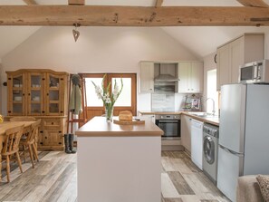 Une cuisine avec des meubles en bois, un îlot central, un lave-linge et un four à micro-ondes.