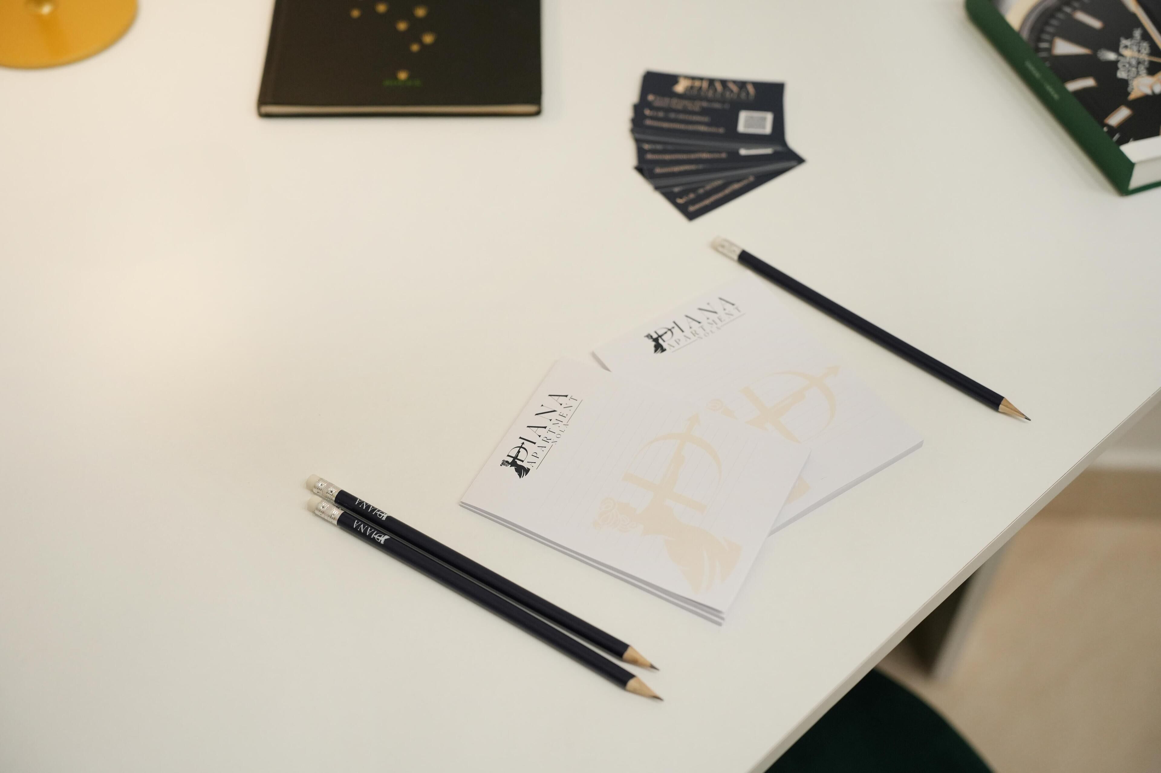 A white table with a book titled 'PANA', two pencils, and a notebook.