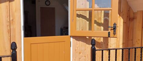 A wooden door with a glass panel, a small window with a chain, and a black metal railing with decorative elements.