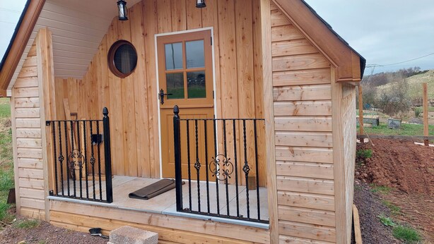Eine Holzhütte mit Veranda, Tür und Fenster.