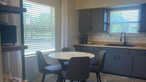 Una cocina moderna con una mesa de comedor redonda, sillas grises y una lámpara colgante.