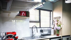 A modern kitchen with a red kettle, a Siemens washing machine, and a window with blinds.