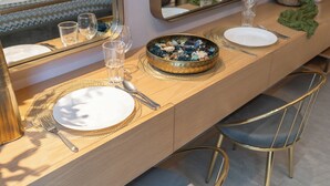 A dining area with a wooden table set for two, including plates, cutlery, and glasses. - Czechin - Modern Studio JVC  (Dubai)