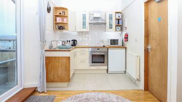 Una cocina compacta con estufa, microondas y armarios.