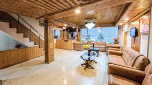 Eine geräumige Lobby mit Holzboden, einer Treppe, einem Empfangstresen und einer Sofaecke.