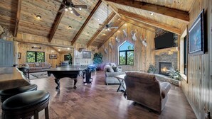 A spacious living area with a pool table, comfortable seating, a fireplace, and a large TV. - Wolf Ridge- Deadwood South Dakota (Sturgis)