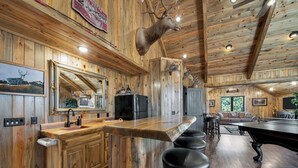 A rustic cabin interior with a wooden bar, a large mirror, and a mounted deer head. - Wolf Ridge- Deadwood South Dakota (Sturgis)