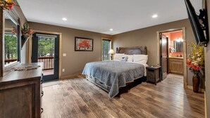 A bedroom with a bed, bedside table, and a window with a view of trees. - Wolf Ridge- Deadwood South Dakota (Sturgis)