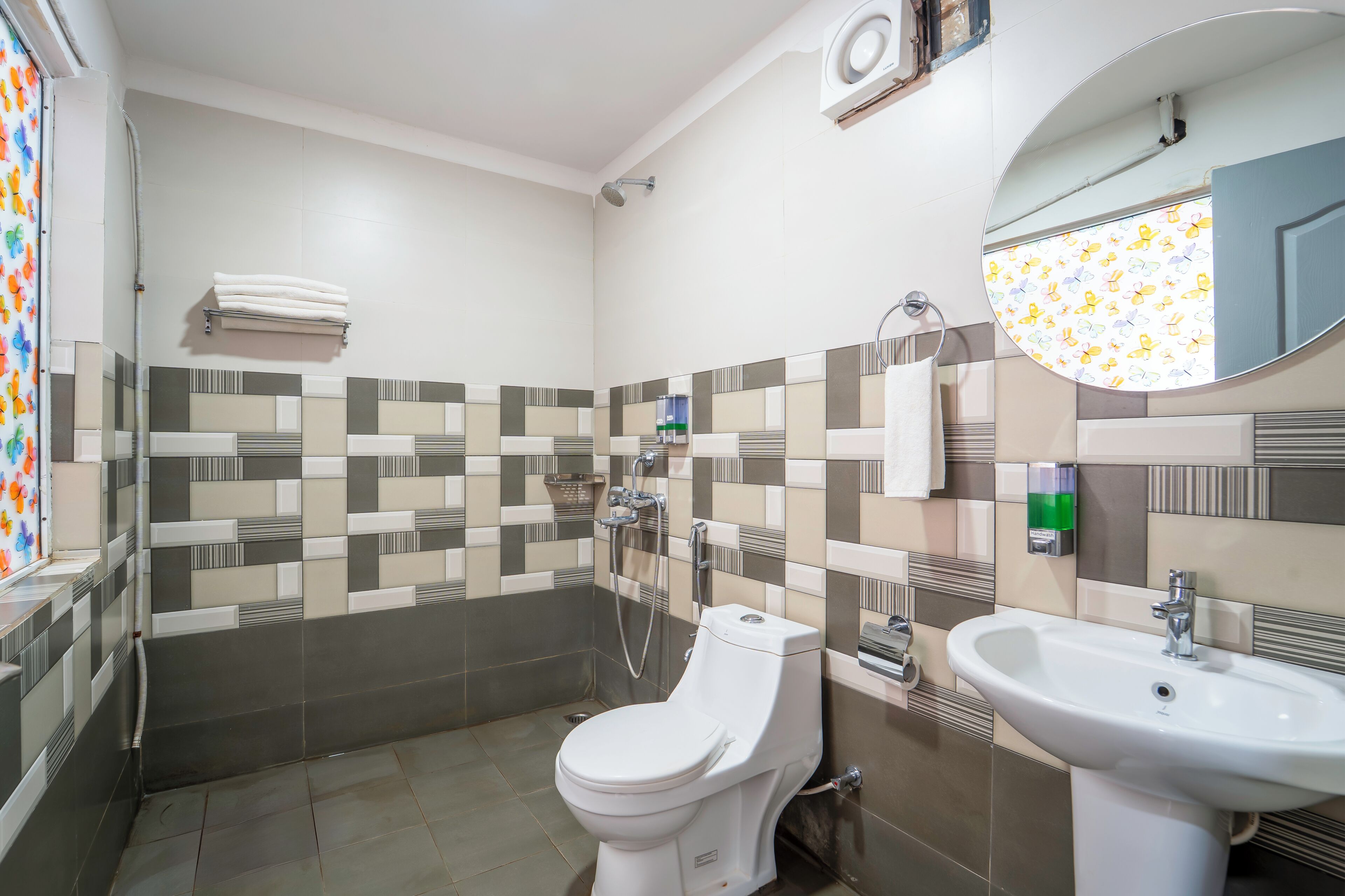 A bathroom with a toilet, sink, shower, and a mirror.